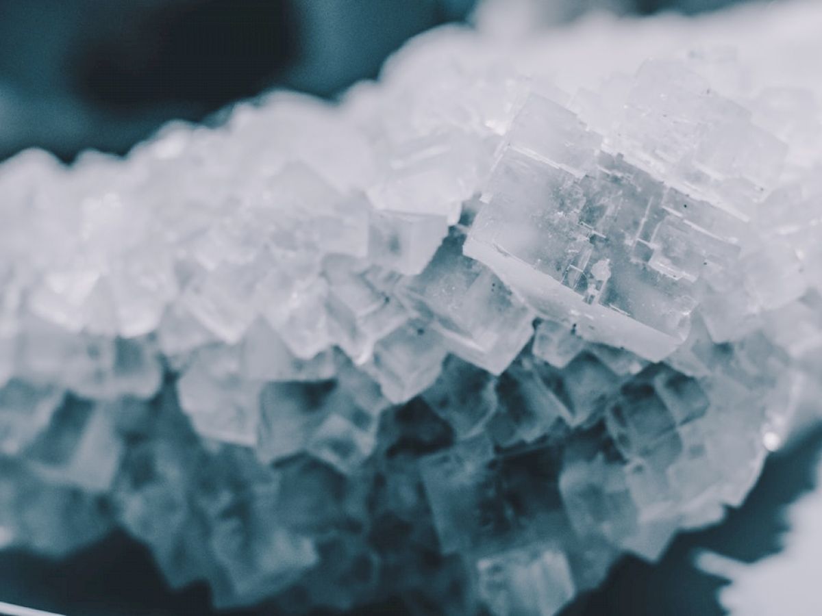 The image shows a close-up of a cluster of clear cubic crystals, possibly salt or quartz, arranged in a rough, irregular formation.