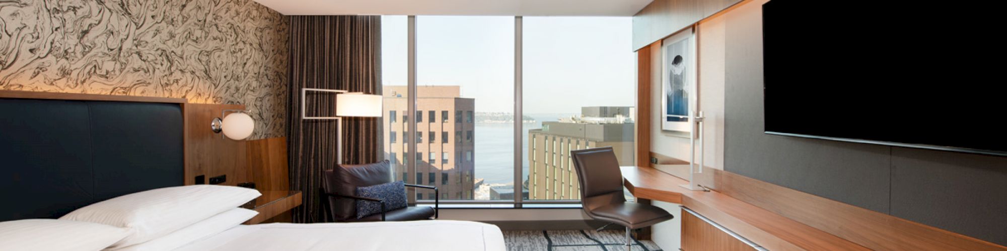 A modern hotel room with a large bed, desk, chair, television, and a window with a cityscape view in the background ends the sentence.